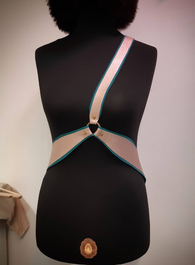 Pink and teal harness accessory on black dress form